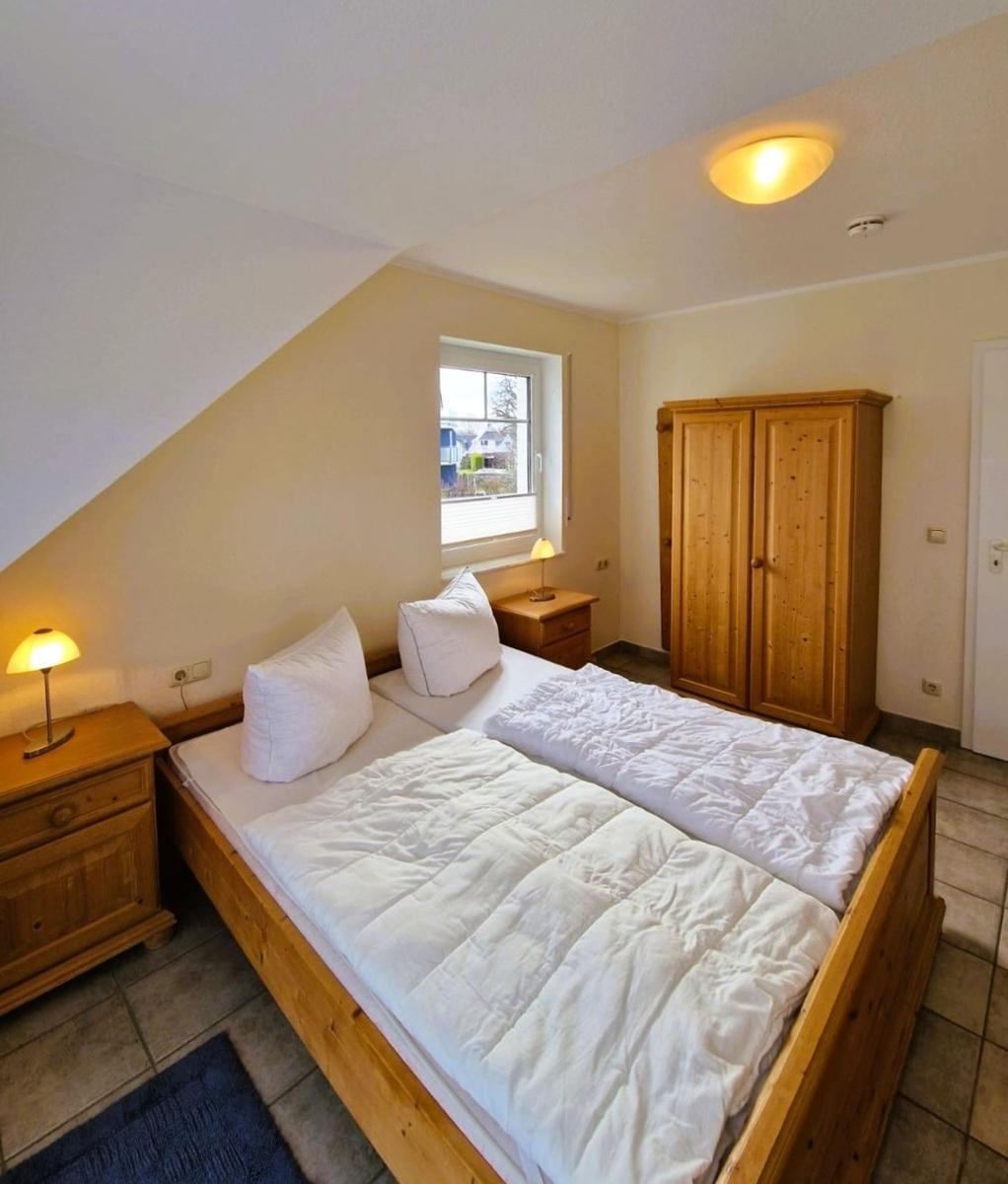 Schlafzimmer mit Doppelbett, Holzmöbel und Fenster