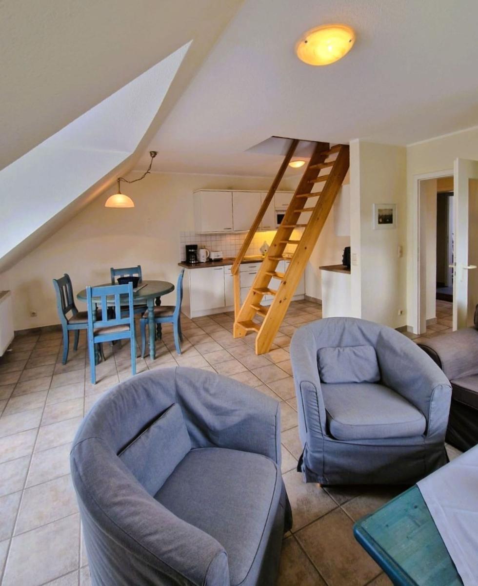 Wohn- und Essbereich mit Küchenzeile und Holztreppe.