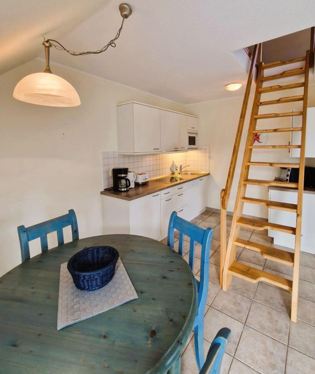 Küche mit Essbereich und Holztreppe zur Unterkunft.