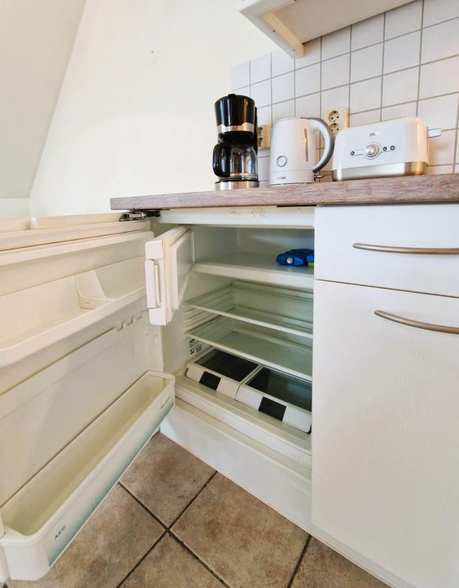 Küche mit offener Kühlschranktür, Kaffeemaschine, Kaffeemaschine und Toaster auf Arbeitsfläche.