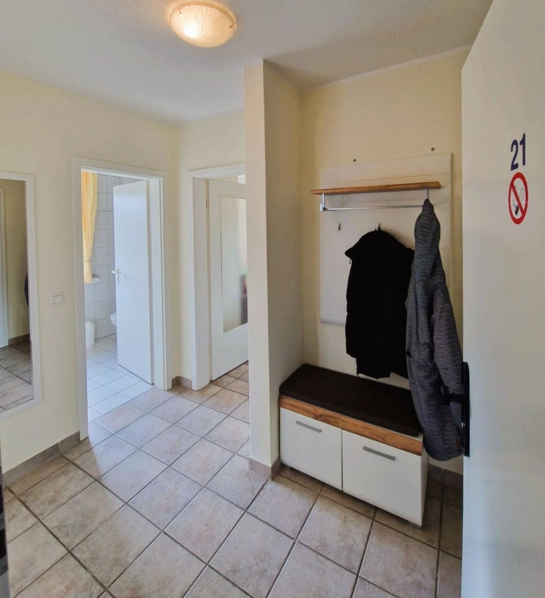 Eingangsbereich mit Garderobe, Sitzbank und Blick in Bad und Schlafzimmer.