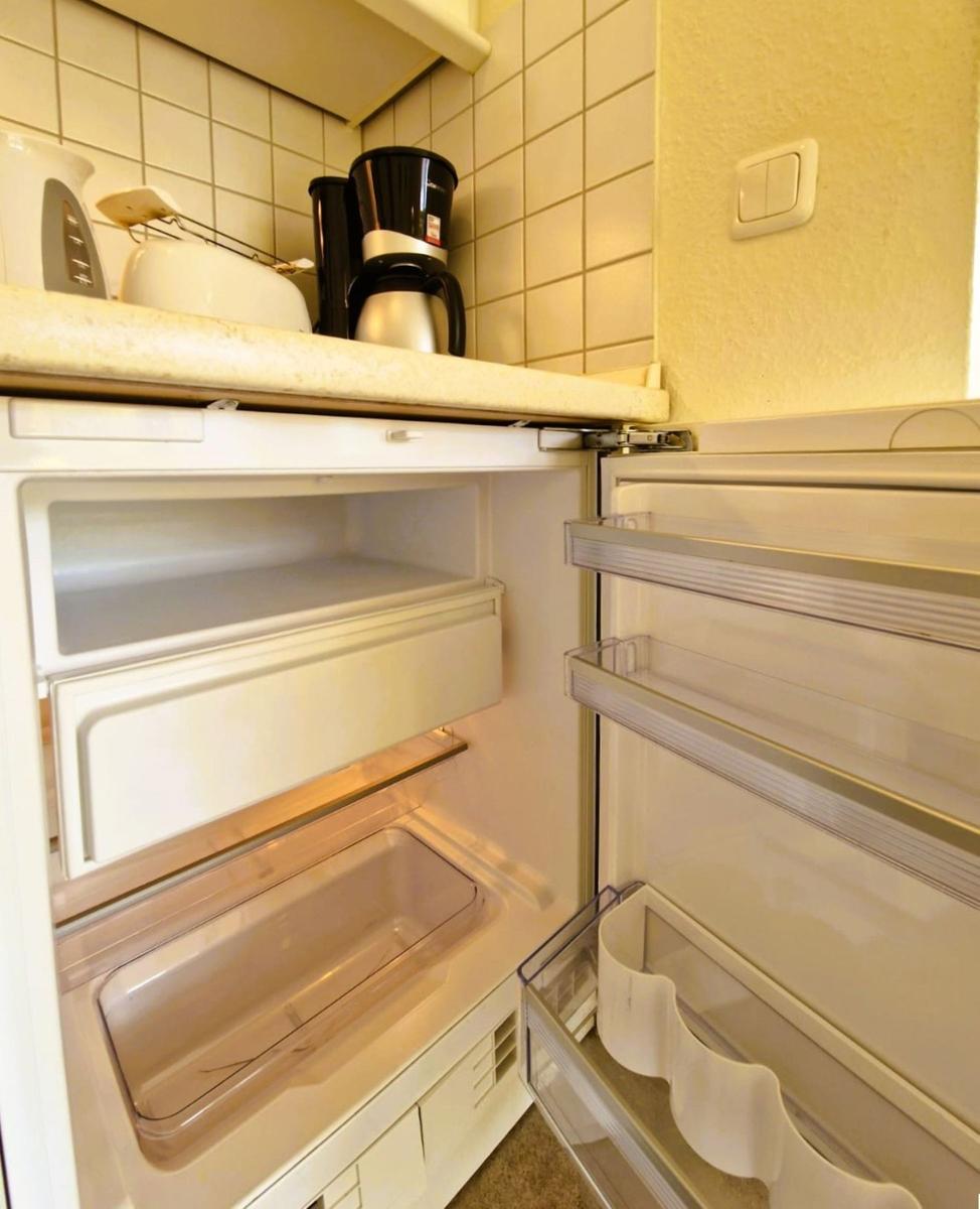 Kühlschrank mit offener Tür, darin sind Schubladen und Fächer sichtbar.