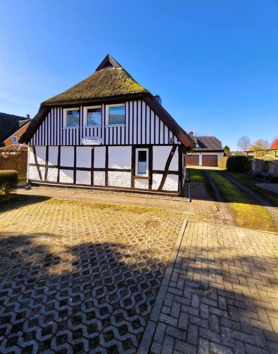 Holiday home with half-timbered structure and thatched roof. Garden with paved path.
