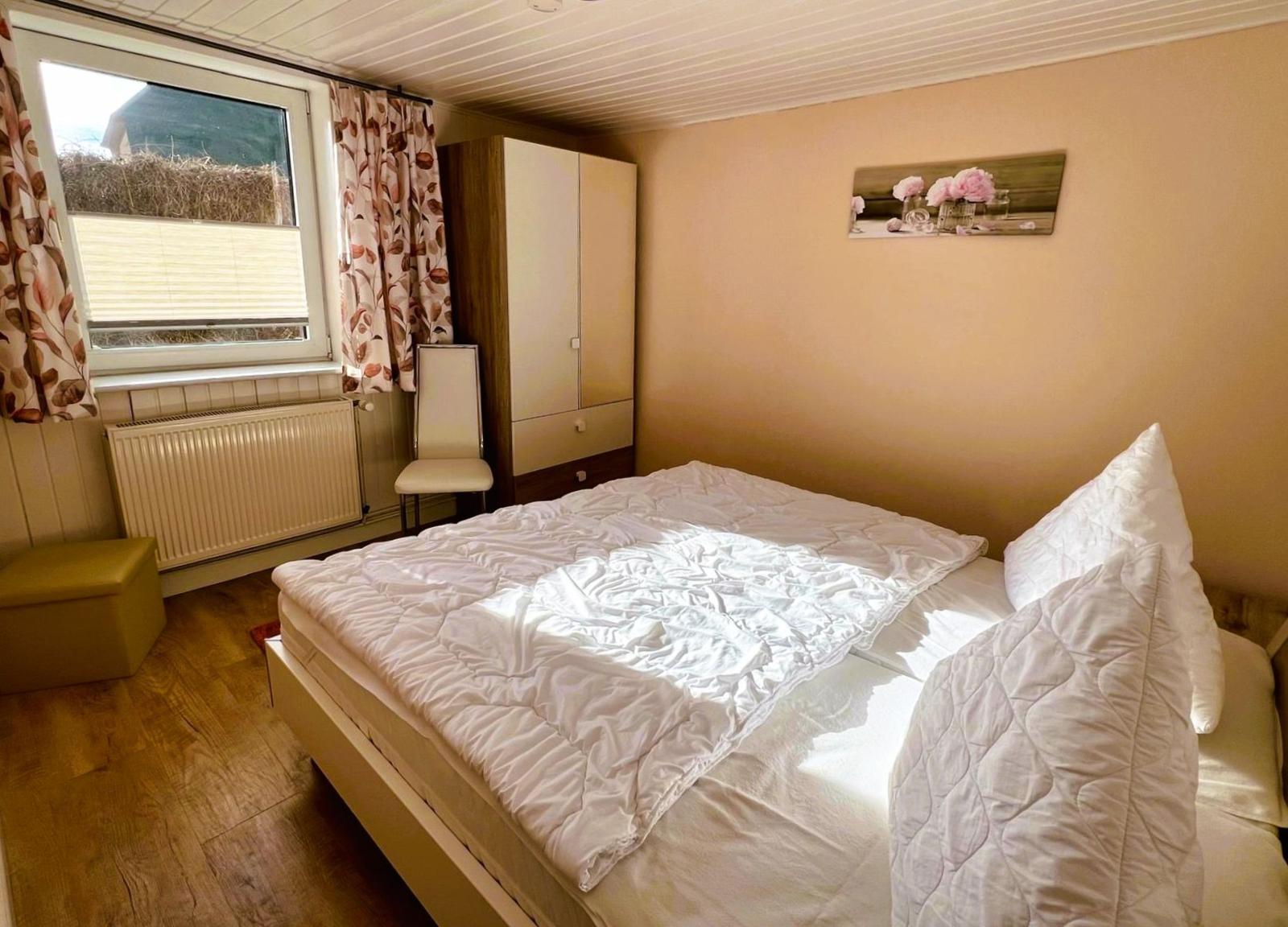 Bedroom with bed, wardrobe, and window. Wall art with flowers.