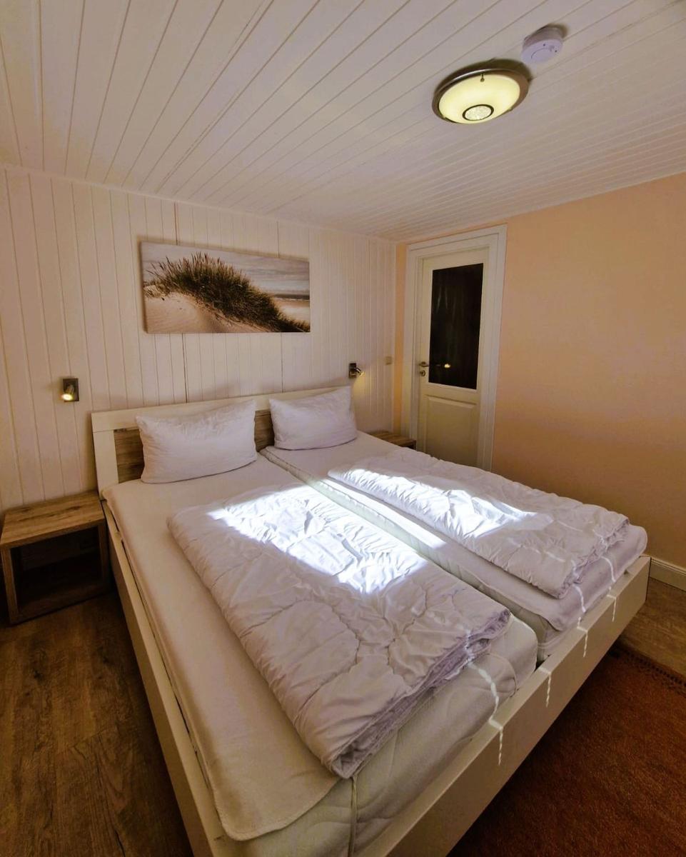 Bedroom with double bed, wooden floor, and wall art.