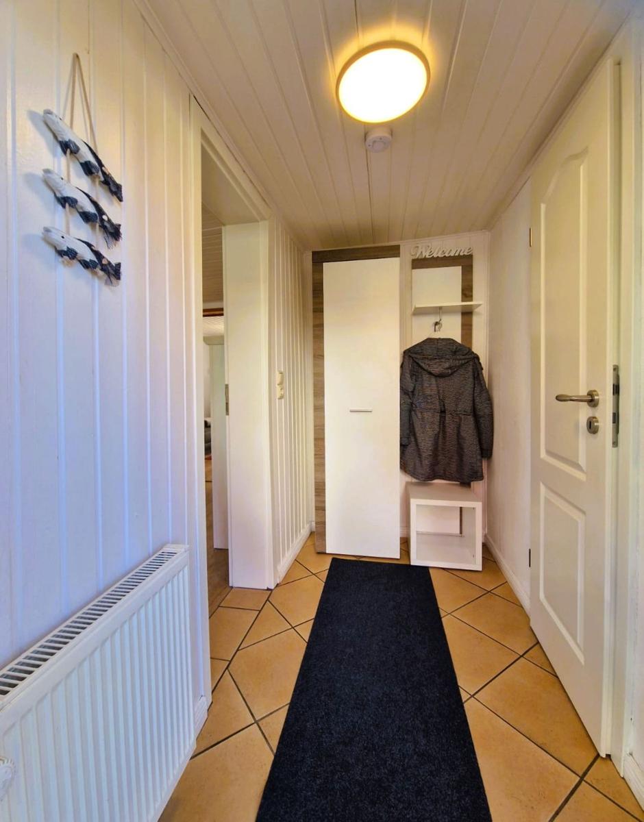 Hallway with rug, coat stand, and wall decoration