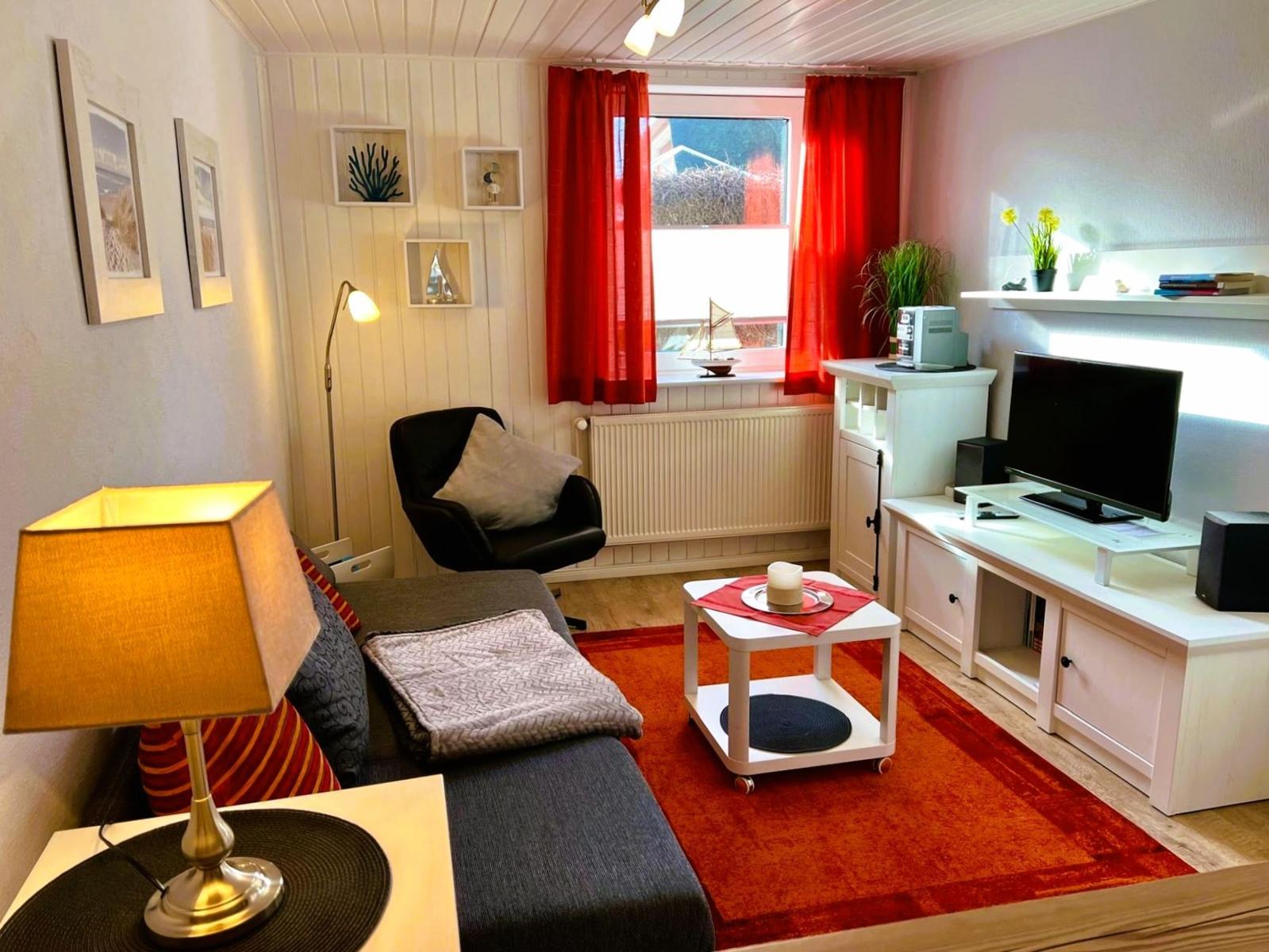 Living room with sofa, armchair, TV, and red rug.