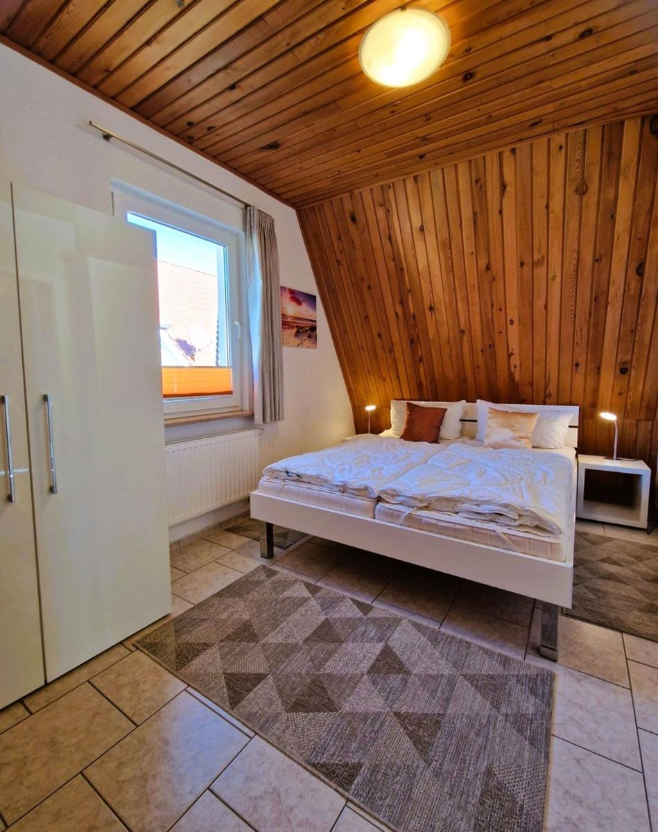 Bedroom with double bed, wooden wall, and window.