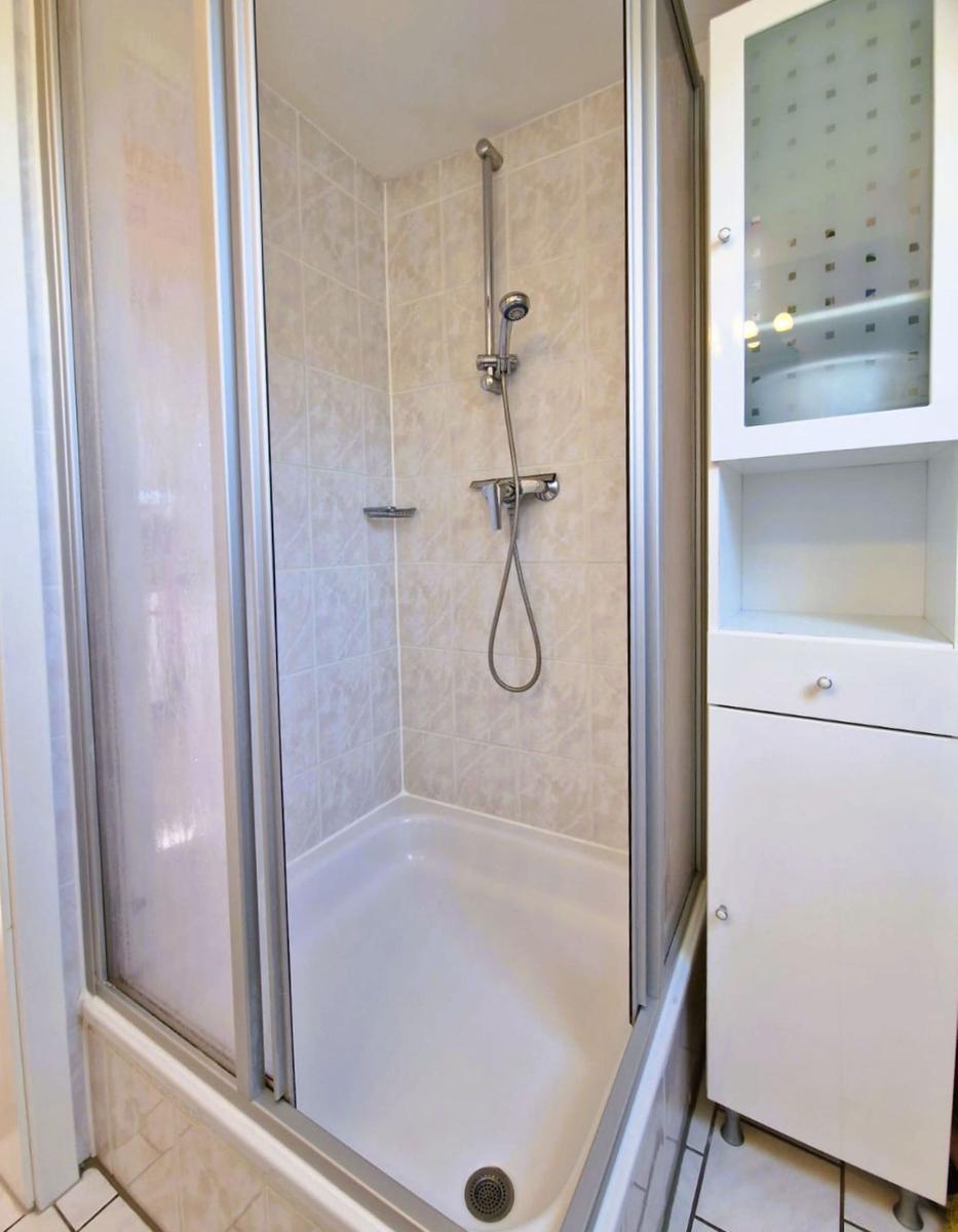 Shower cabin with shower head and adjacent white cabinet