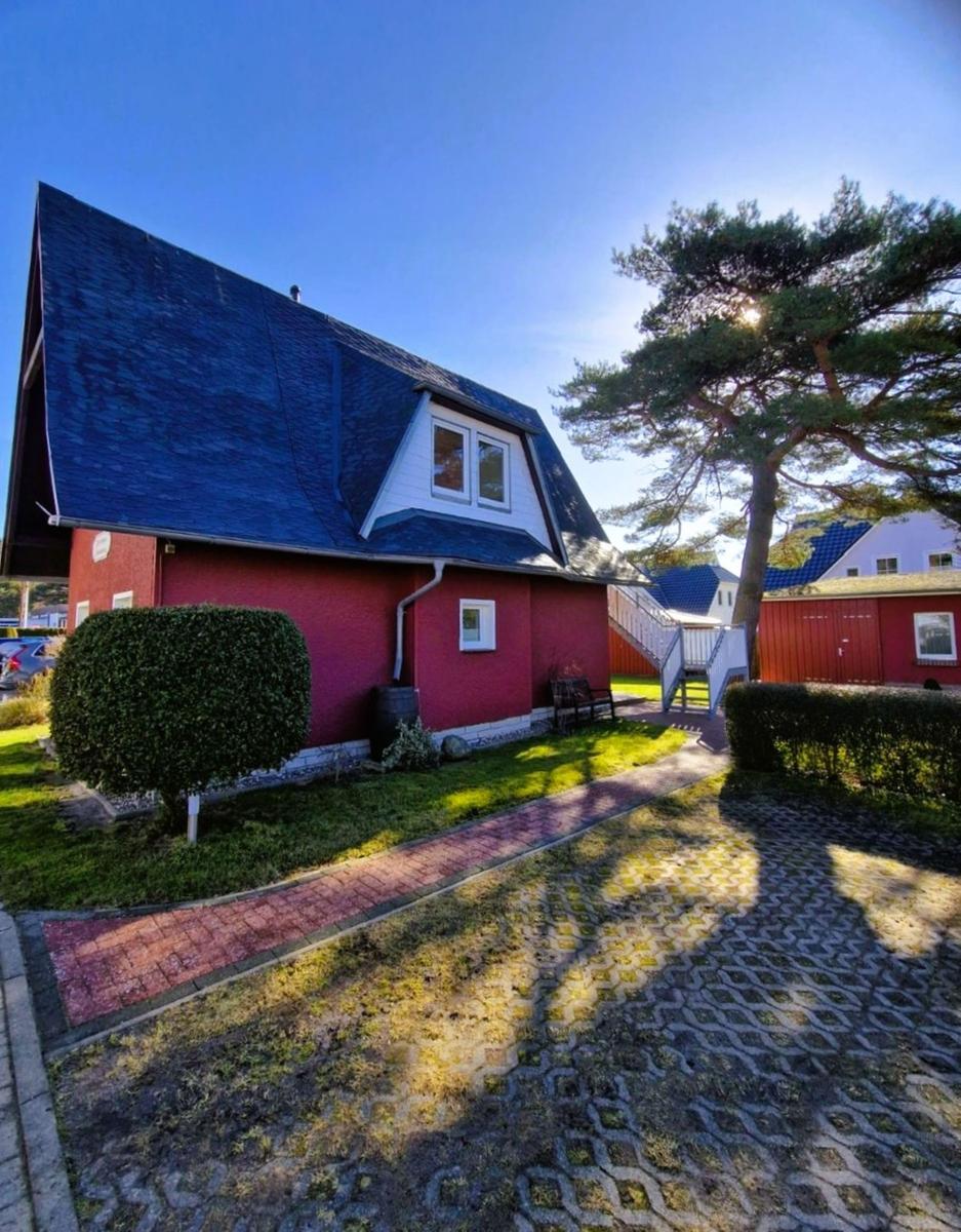 Red house with dark roof and paved path in the front yard