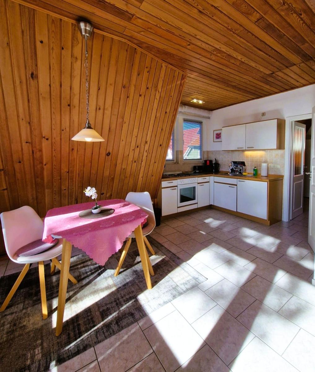 Dining area with table, chairs, and kitchen area with white cabinets.