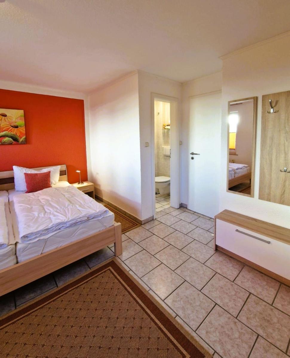 Bedroom with bed, wall art, and hallway to toilet and shower.