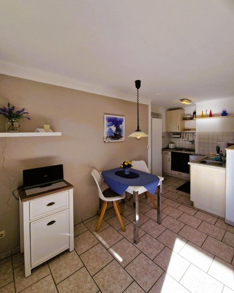 Dining area with table, chairs, and kitchen area in the background.