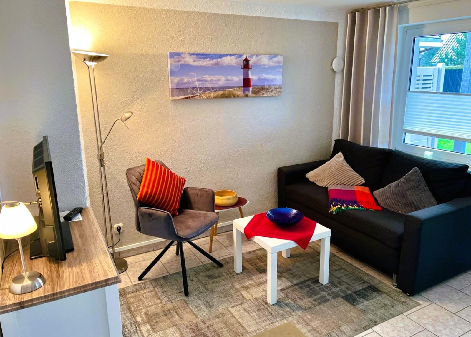 Living room with sofa, armchair, coffee table, and wall art with lighthouse.