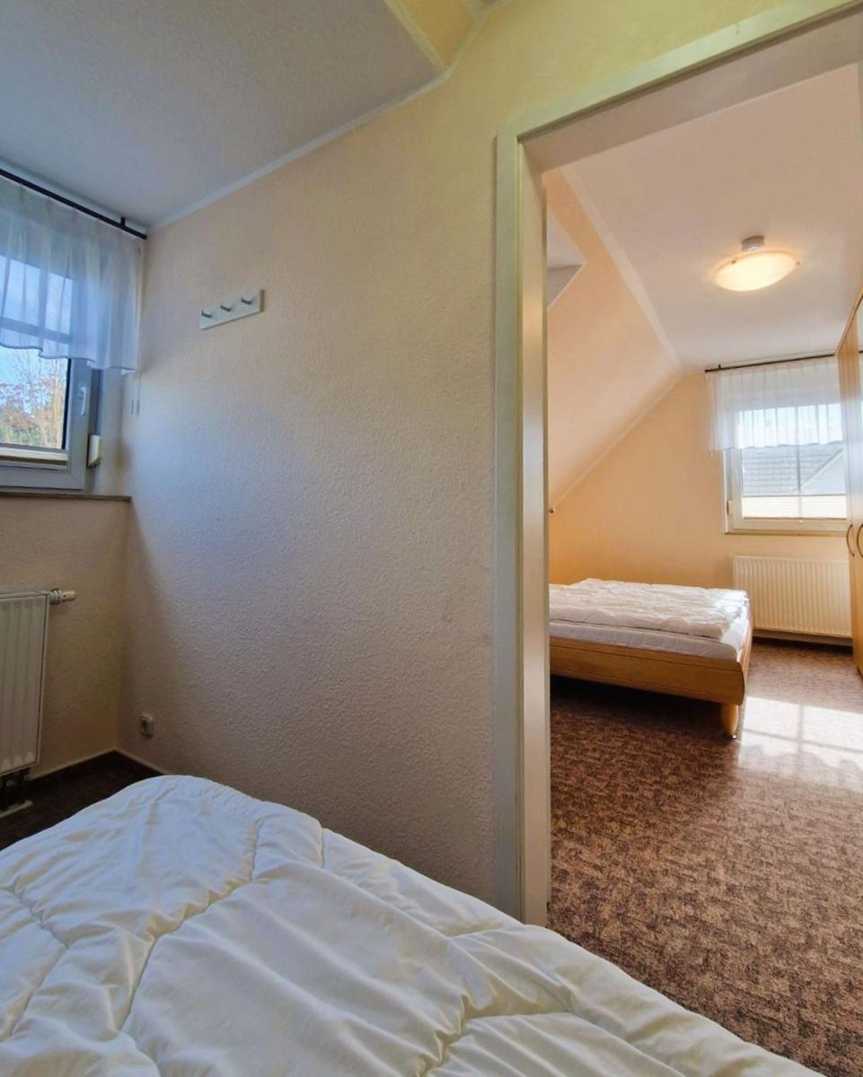 Zwei Schlafzimmer mit Betten, Fenstern und Heizkörpern. Eines mit Dachschrägen.