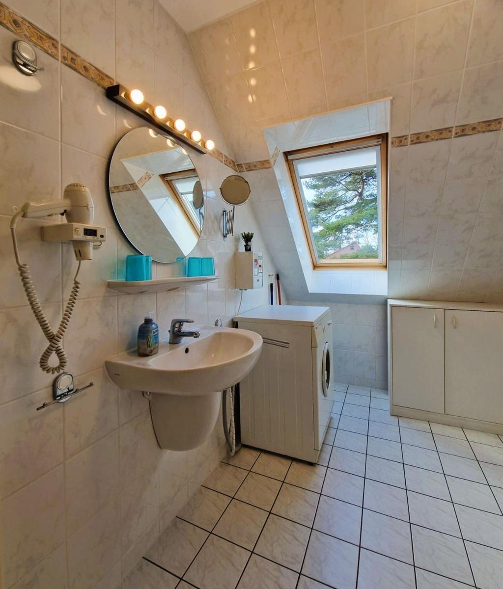 Badezimmer mit Waschmaschine, Spiegel und Dachfenster