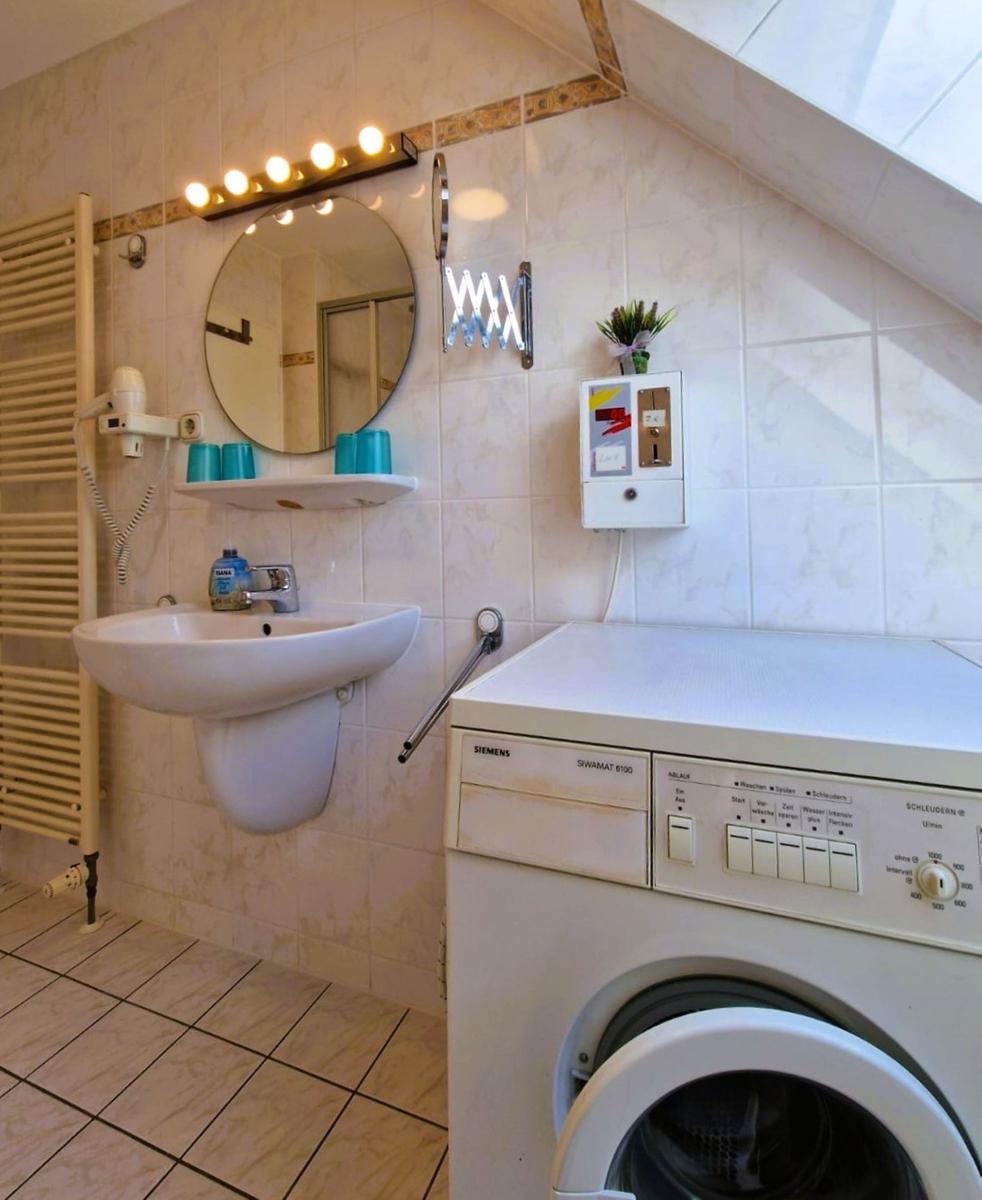 Badezimmer mit Waschmaschine, Spiegel und Handtuchhalter