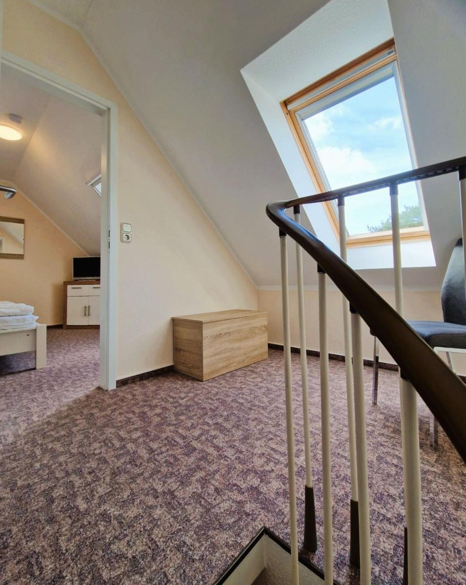 Dachgeschoss mit Dachschrägen, Dachfenster und Holztruhe. Tür führt in Schlafzimmer.