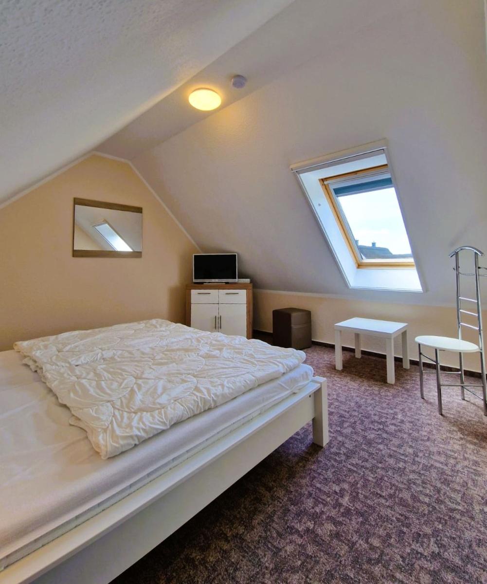 Schlafzimmer mit Dachschrägen, Dachfenster, Bett, Schrank und Tisch.