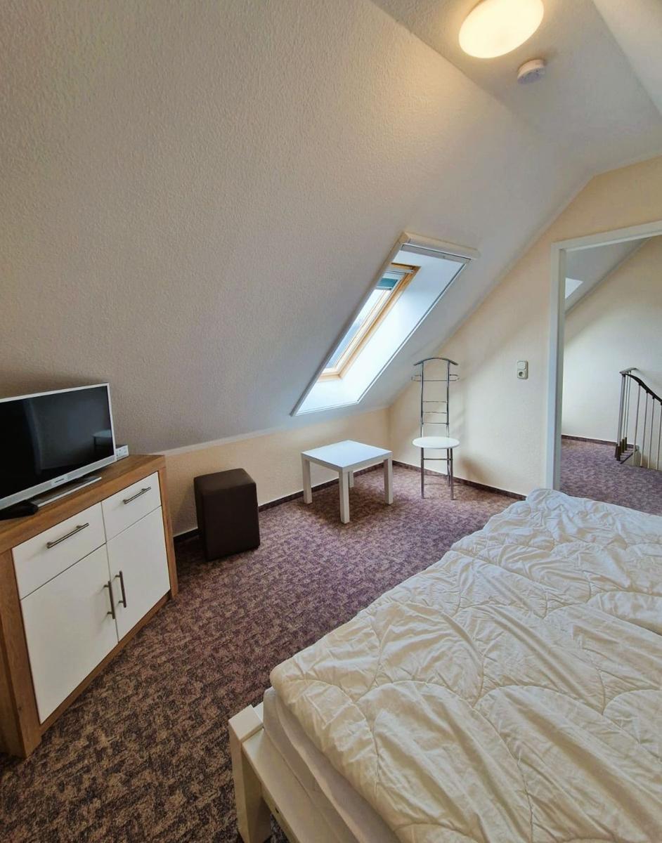 Schlafzimmer mit Dachschrägen, Dachfenster, Bett, Schrank und kleiner Tisch.