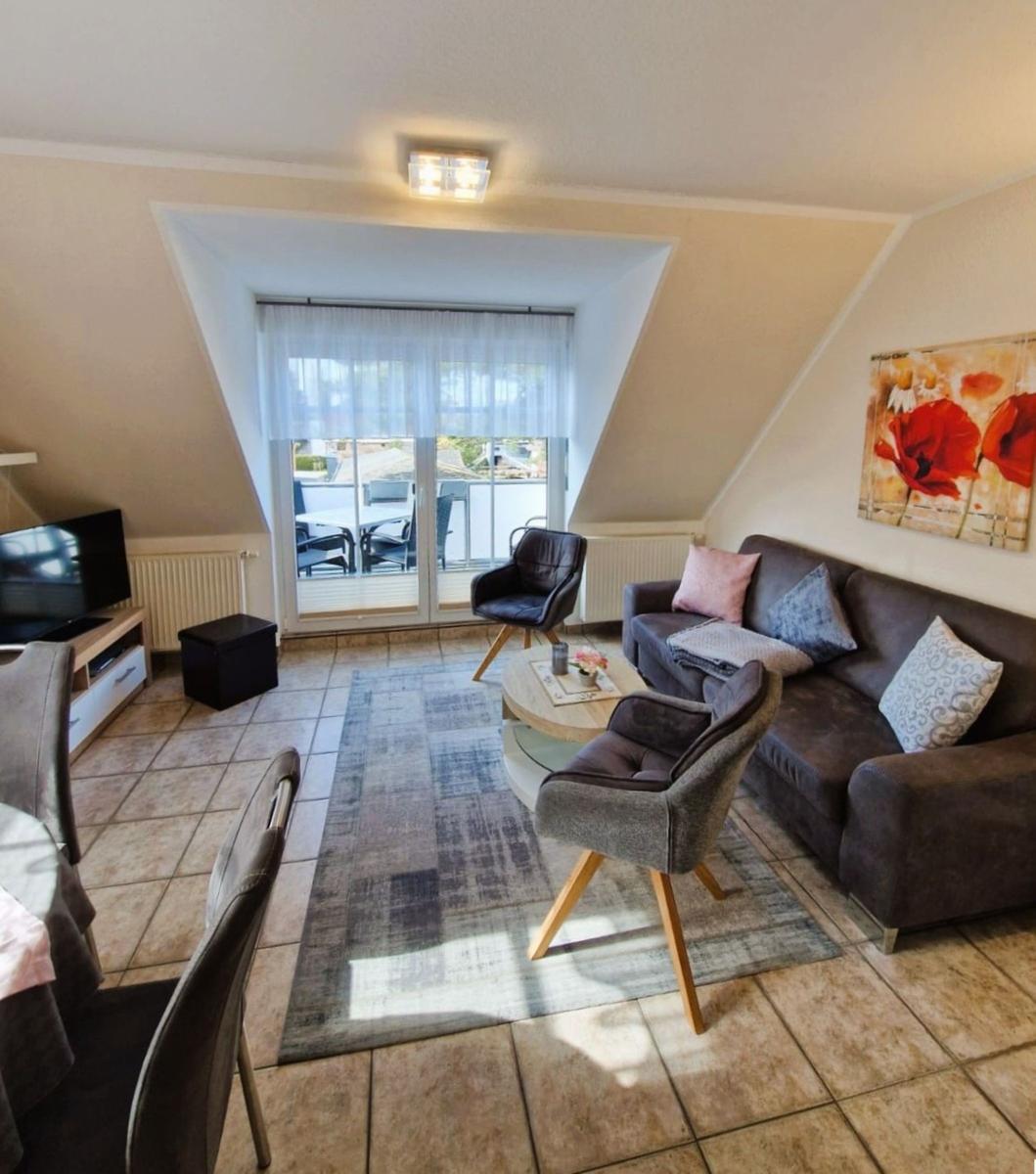 Wohnzimmer mit Sofa, Sesseln und Blick auf Balkon