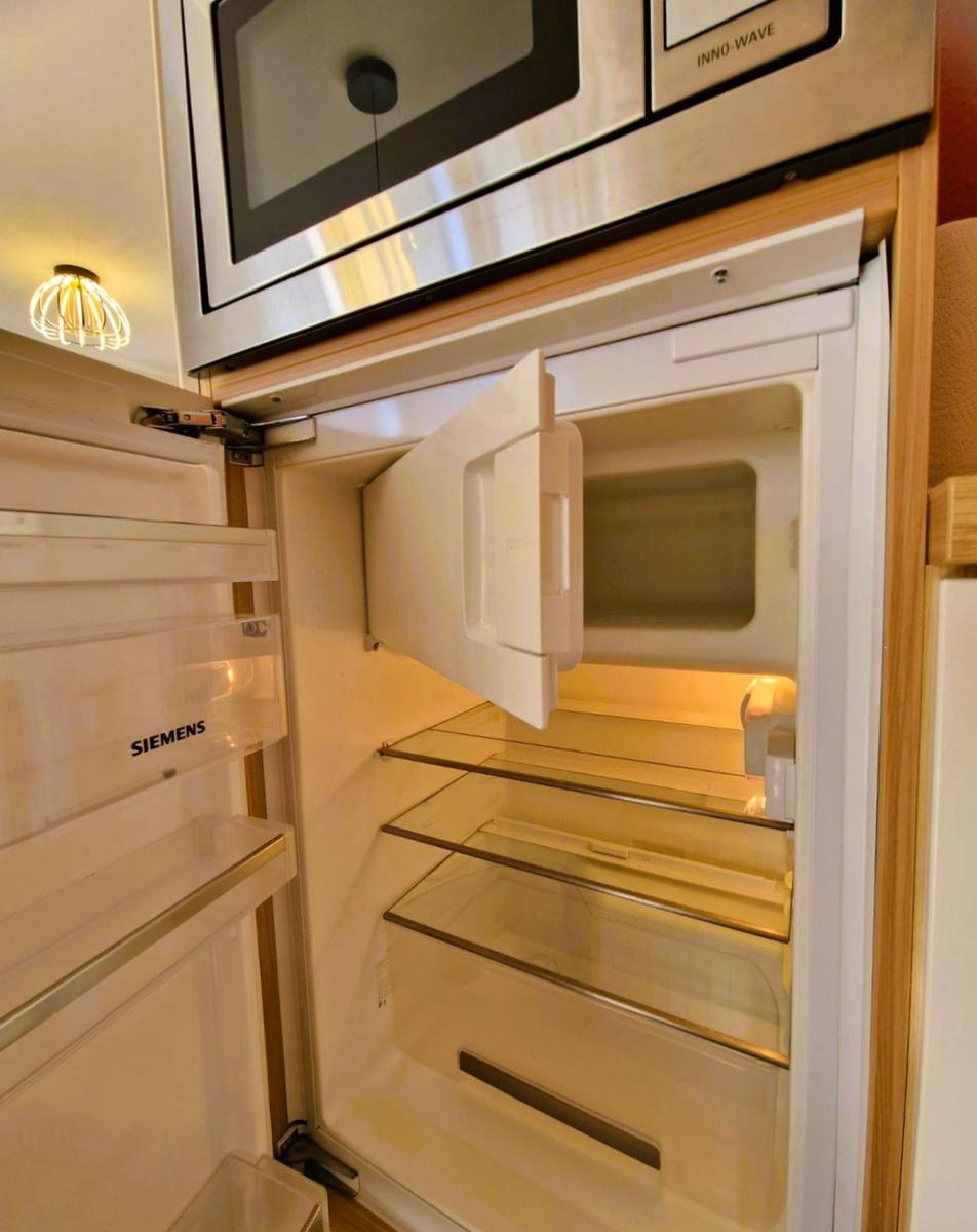 Refrigerator with open door and built-in microwave.