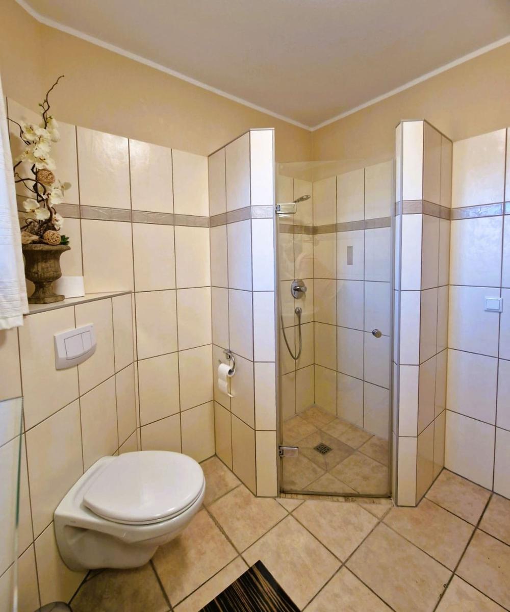 Bathroom with shower, toilet, and tiles