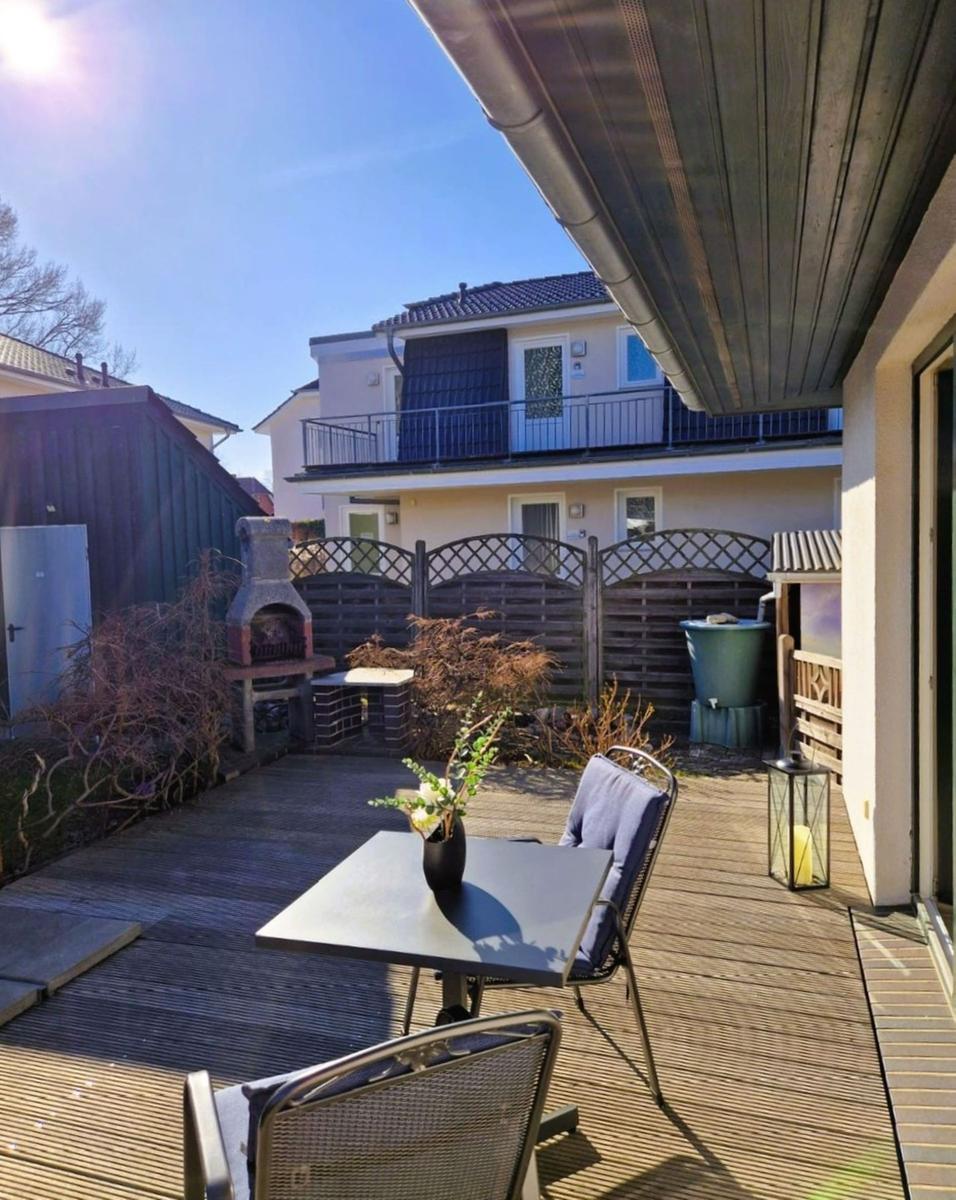 Deck with table, chairs, and grill. Backyard with fence and neighboring house.