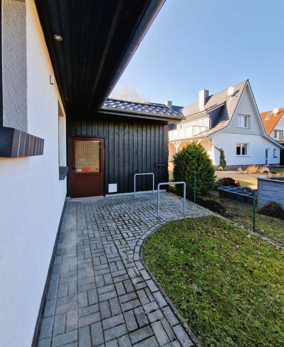 Entrance area with door, walkway, and lawn. Backyard with garden and neighboring house.