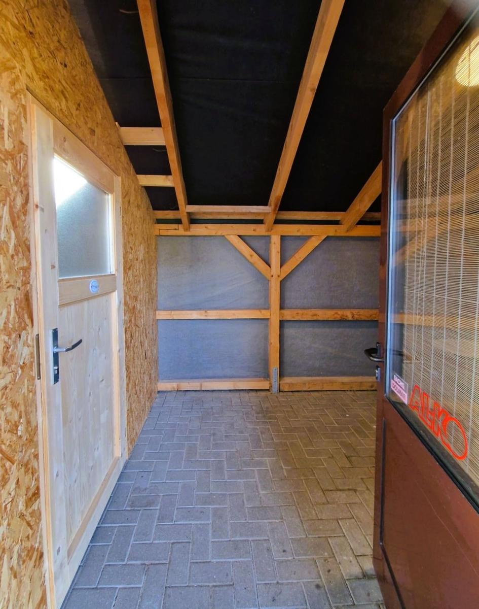 Backyard with wooden frame, stone floor, and two doors.