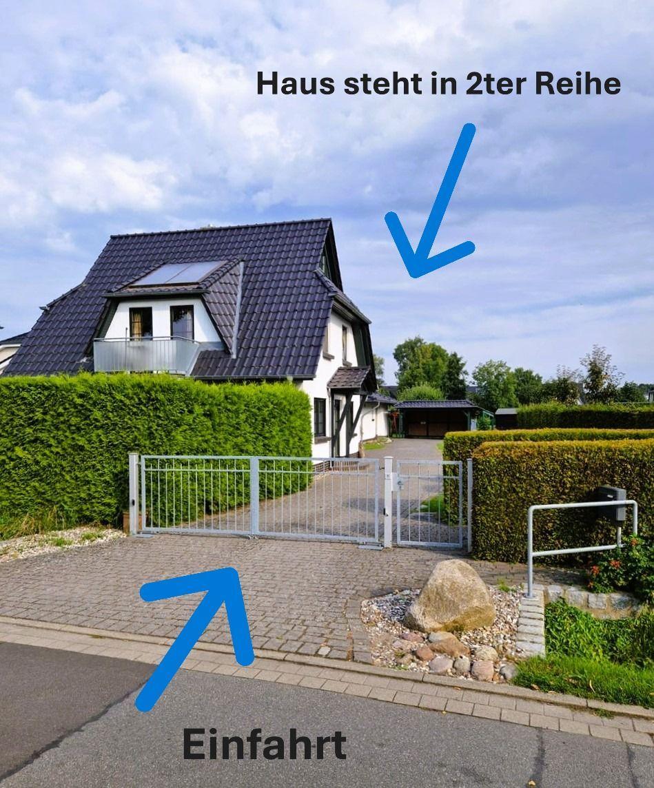 House in second row with driveway and closed gate.