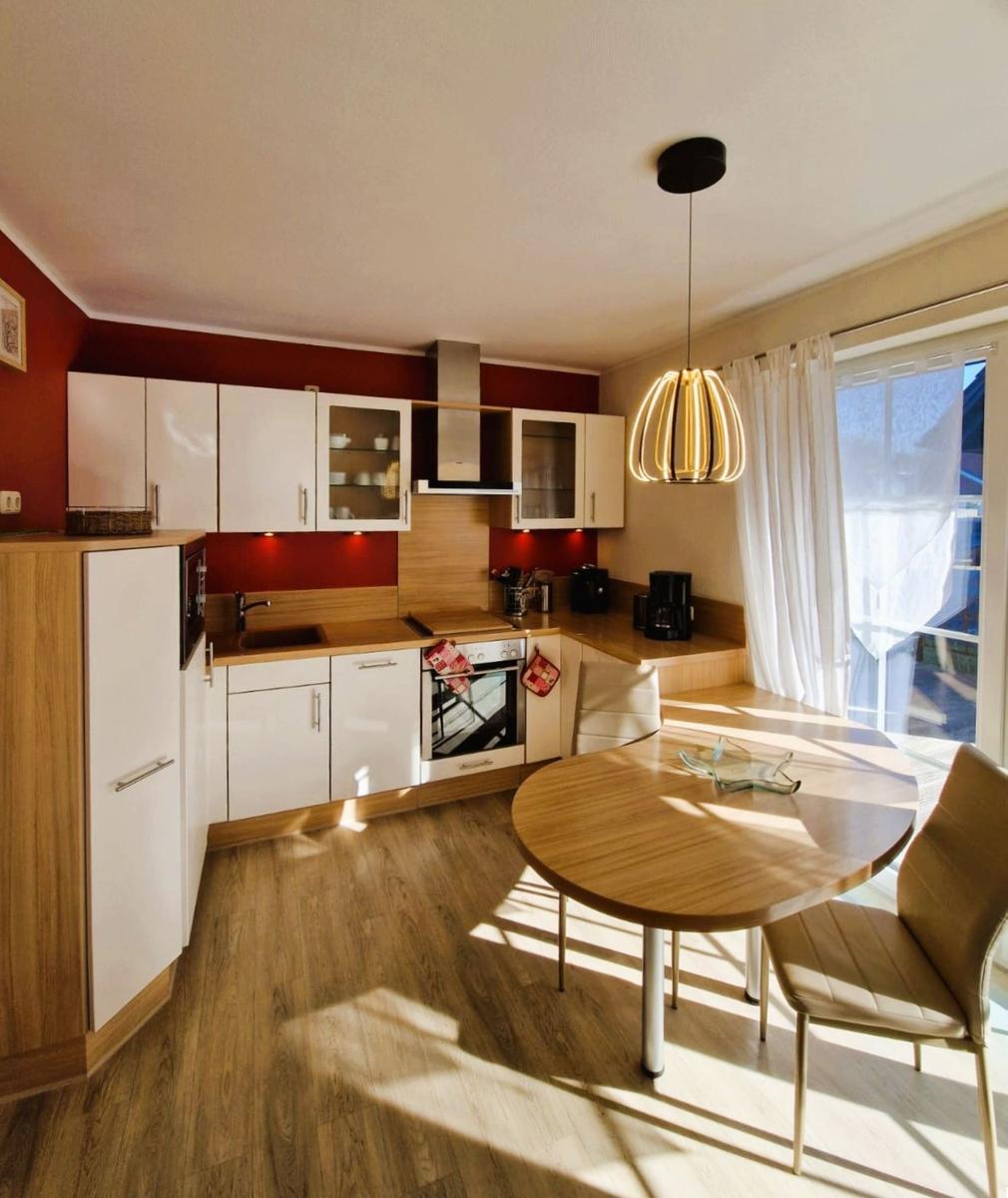 Kitchen with dining area, wooden floor, and window to terrace.