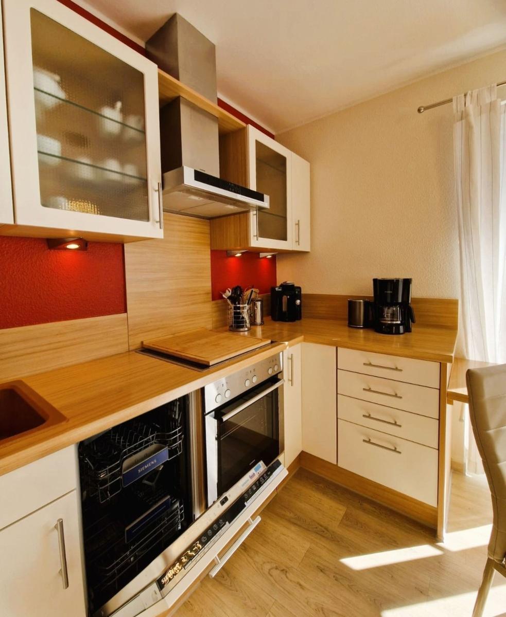 Kitchen with wooden surfaces, integrated dishwasher and oven, and coffee machine.