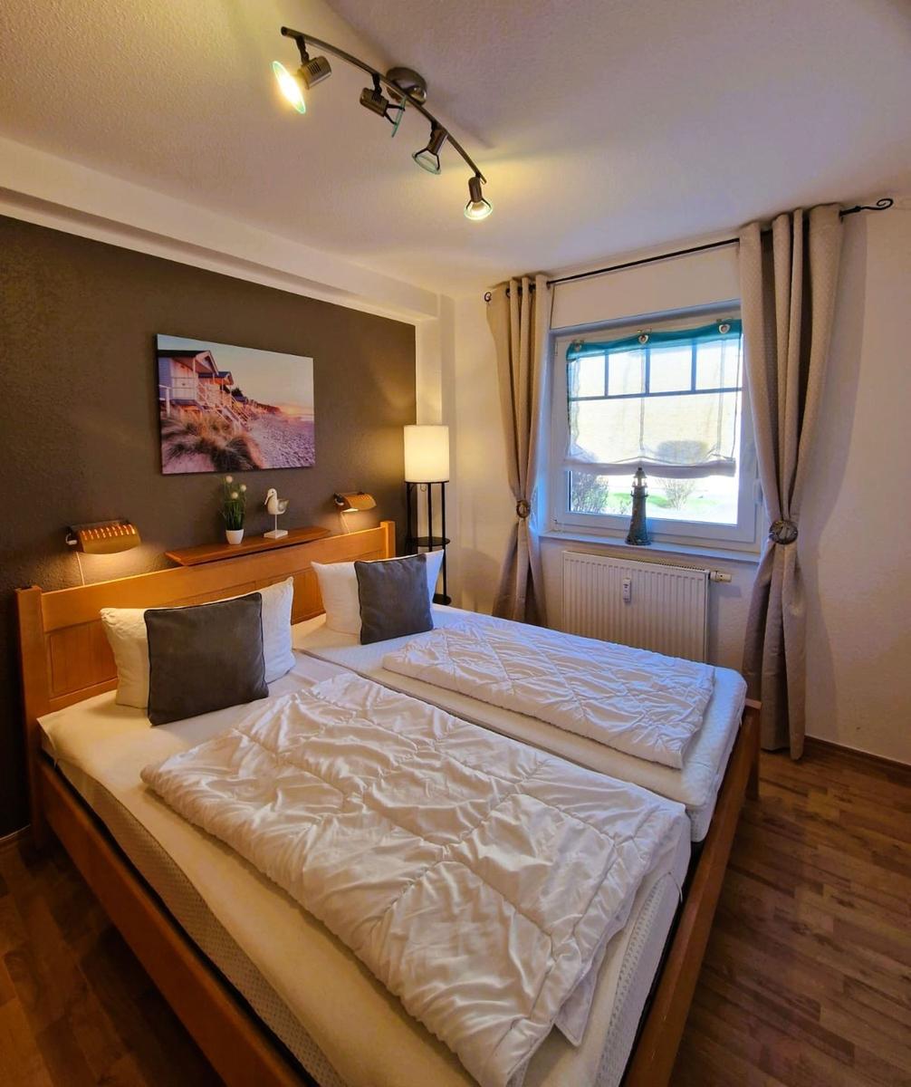 Schlafzimmer mit Doppelbett, Fenster und Wandbild.