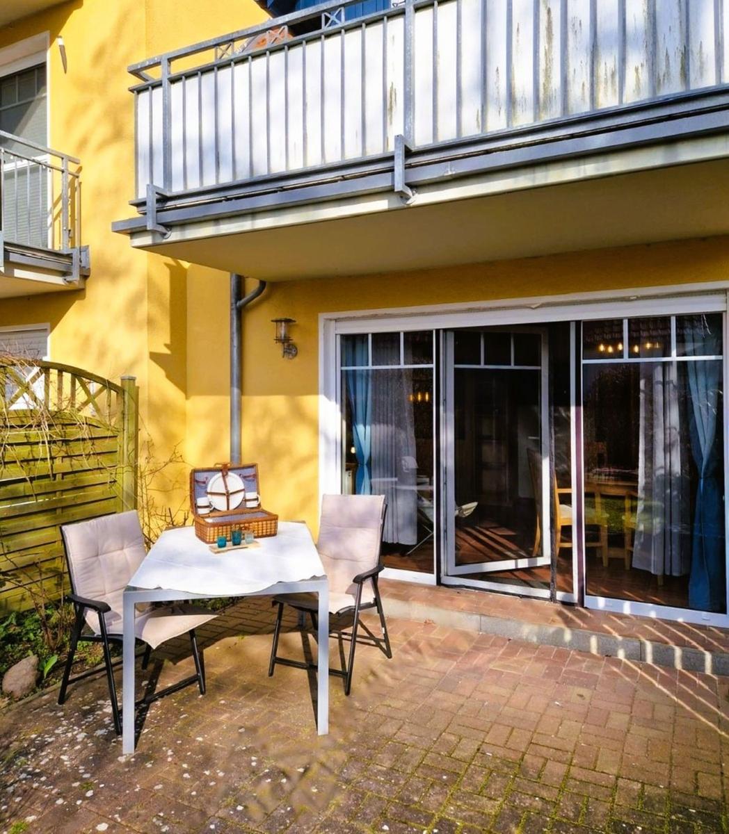 Helle Terrasse mit Tisch, zwei Stühlen und Picknickkorb. Glastüren führen ins Innere.