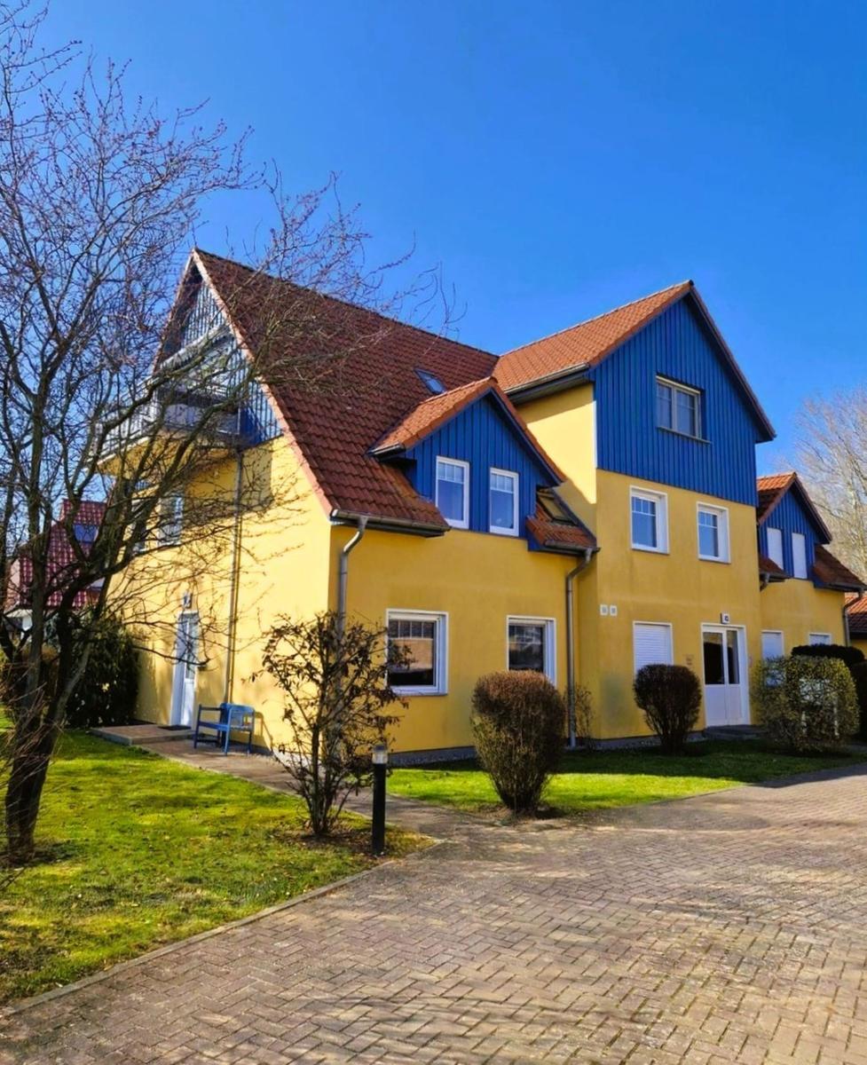 Fassade eines zweistöckigen Hauses mit gelbem und blauem Anstrich und rotem Dach