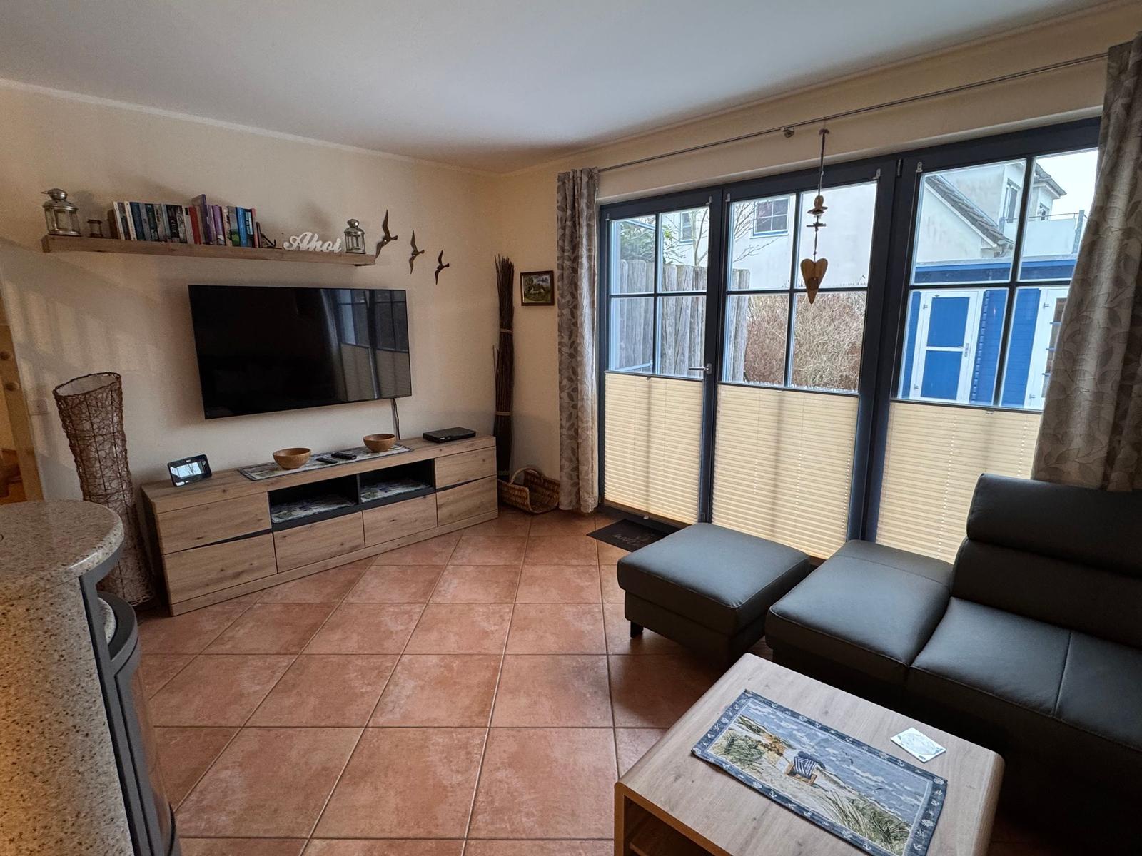 Wohnzimmer mit Sofa, TV und Terrassentür.