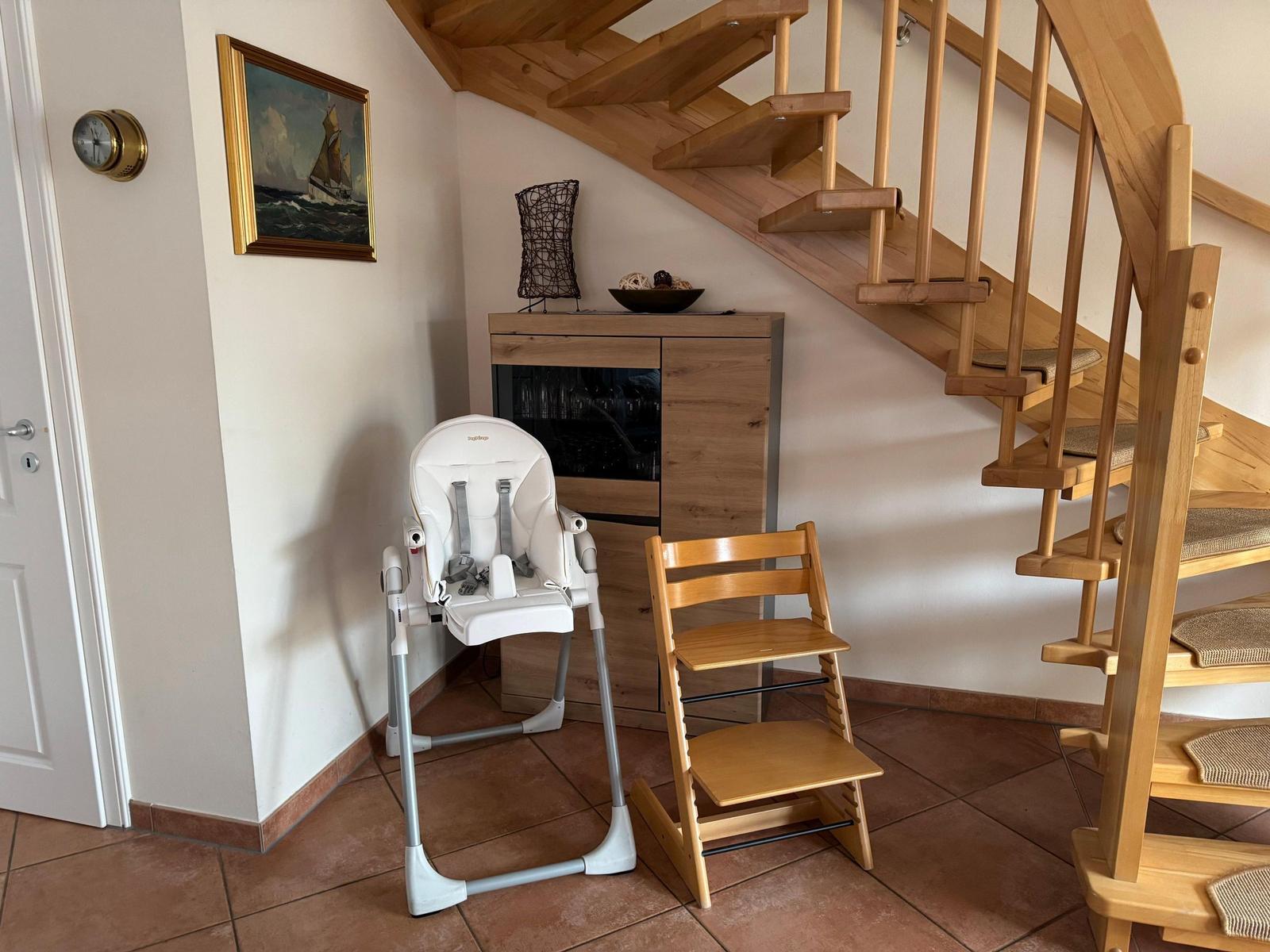 Hochstuhl und Kinderstuhl stehen neben einer Treppe und einem Schrank.