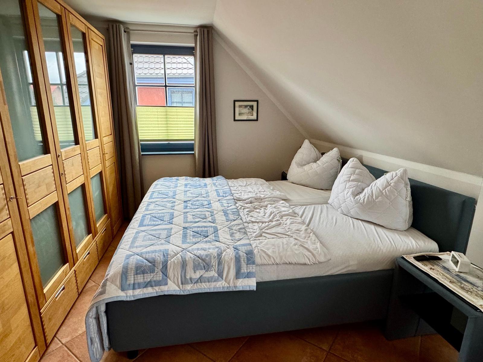 Schlafzimmer mit Doppelbett, Kleiderschrank und Fenster mit Blick.
