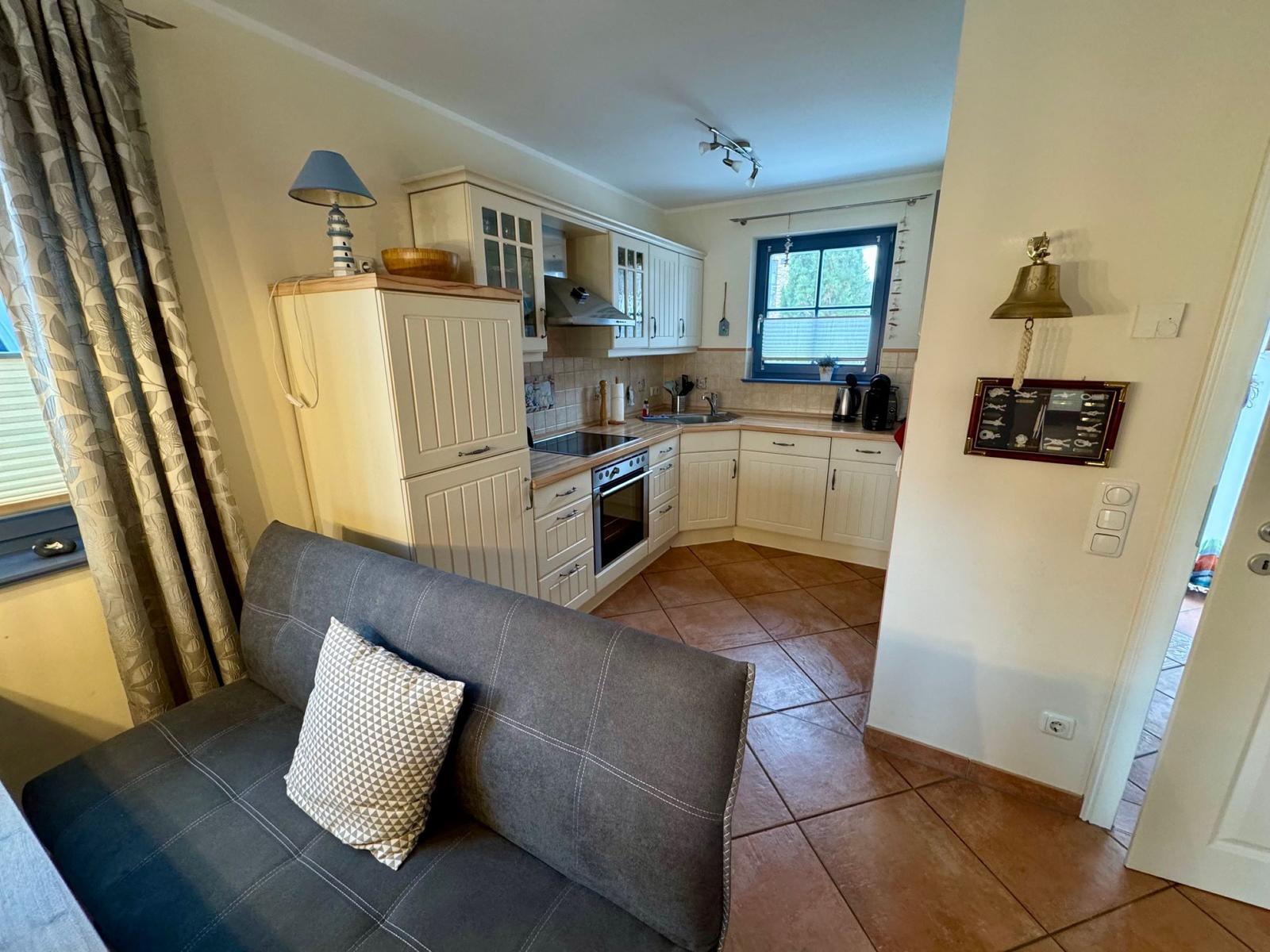 Küche mit weißen Schränken und Sofa im Vordergrund.