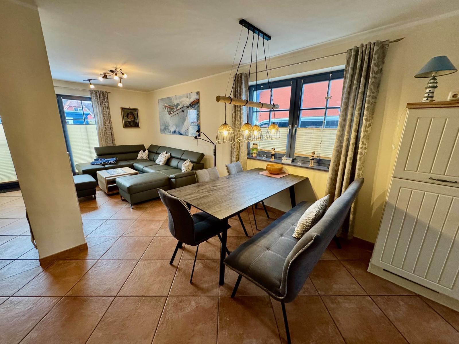 Esszimmer mit Tisch und Bank. Wohnbereich mit Sofa und Fenstern.