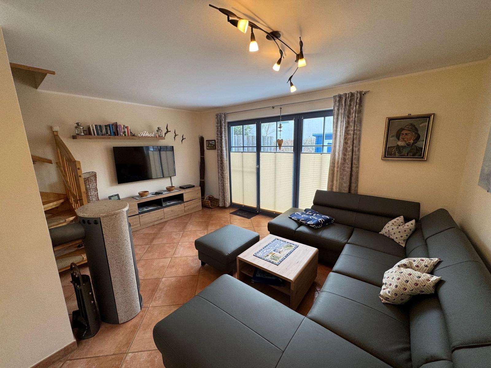 Wohnzimmer mit Sofa, Fernseher und Terrassentür.