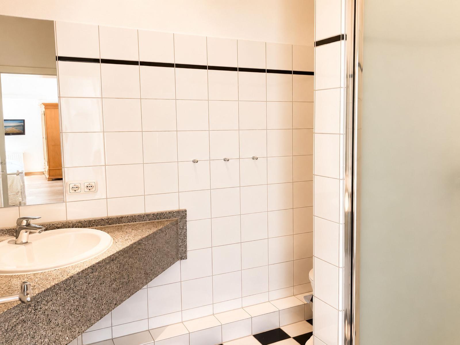Badezimmer mit Waschbecken, Spiegel und Dusche