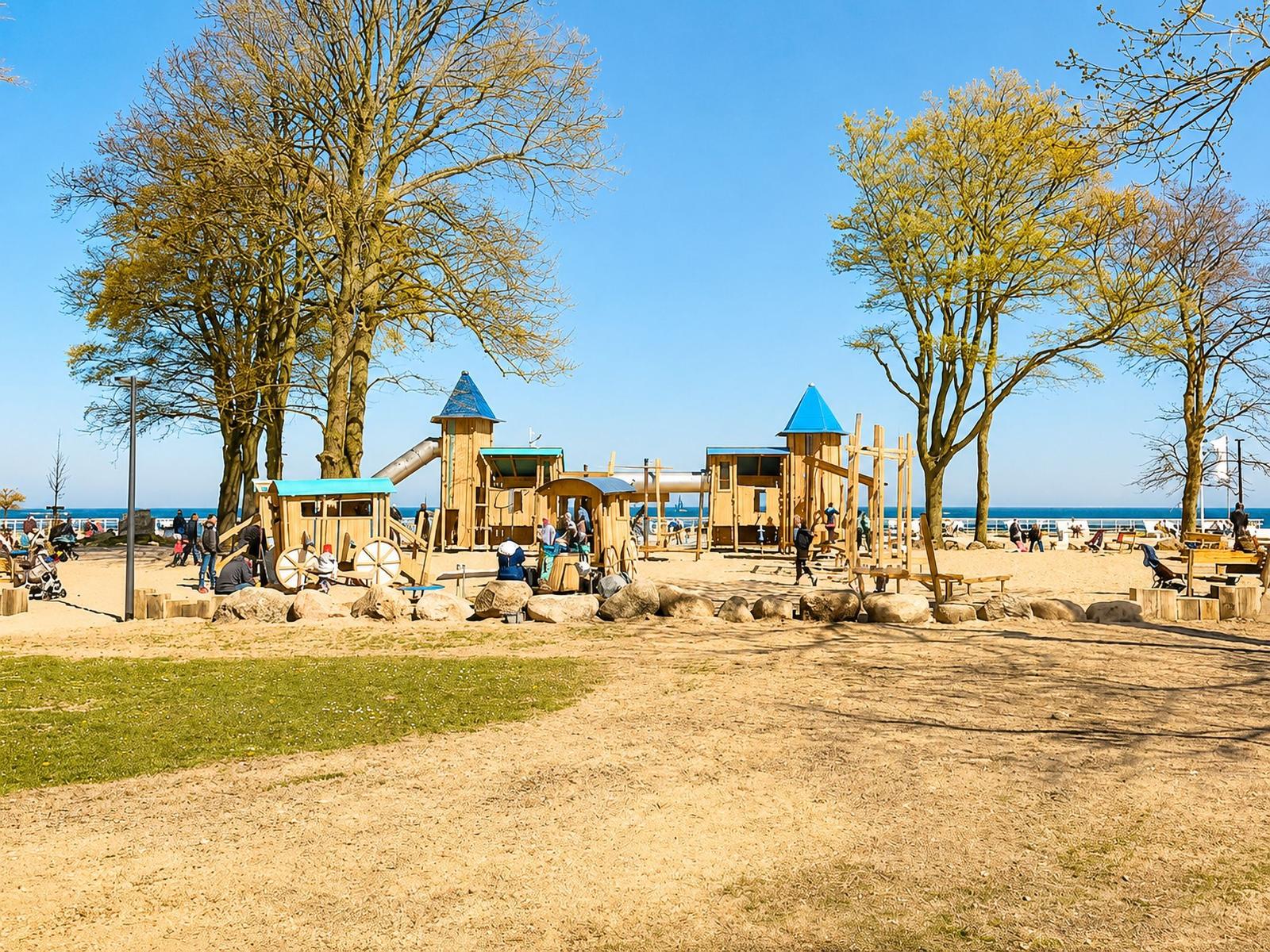 Kinderbereich mit Holzspielgeräten und Bäumen am Strand