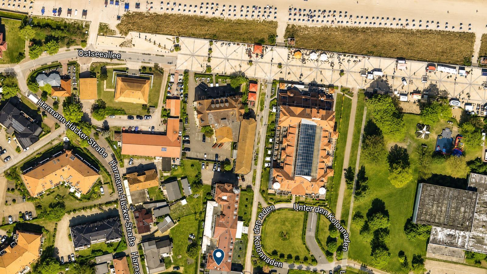 Luftbild von Strandpromenade und umliegenden Gebäuden mit Straßen und Grünflächen.