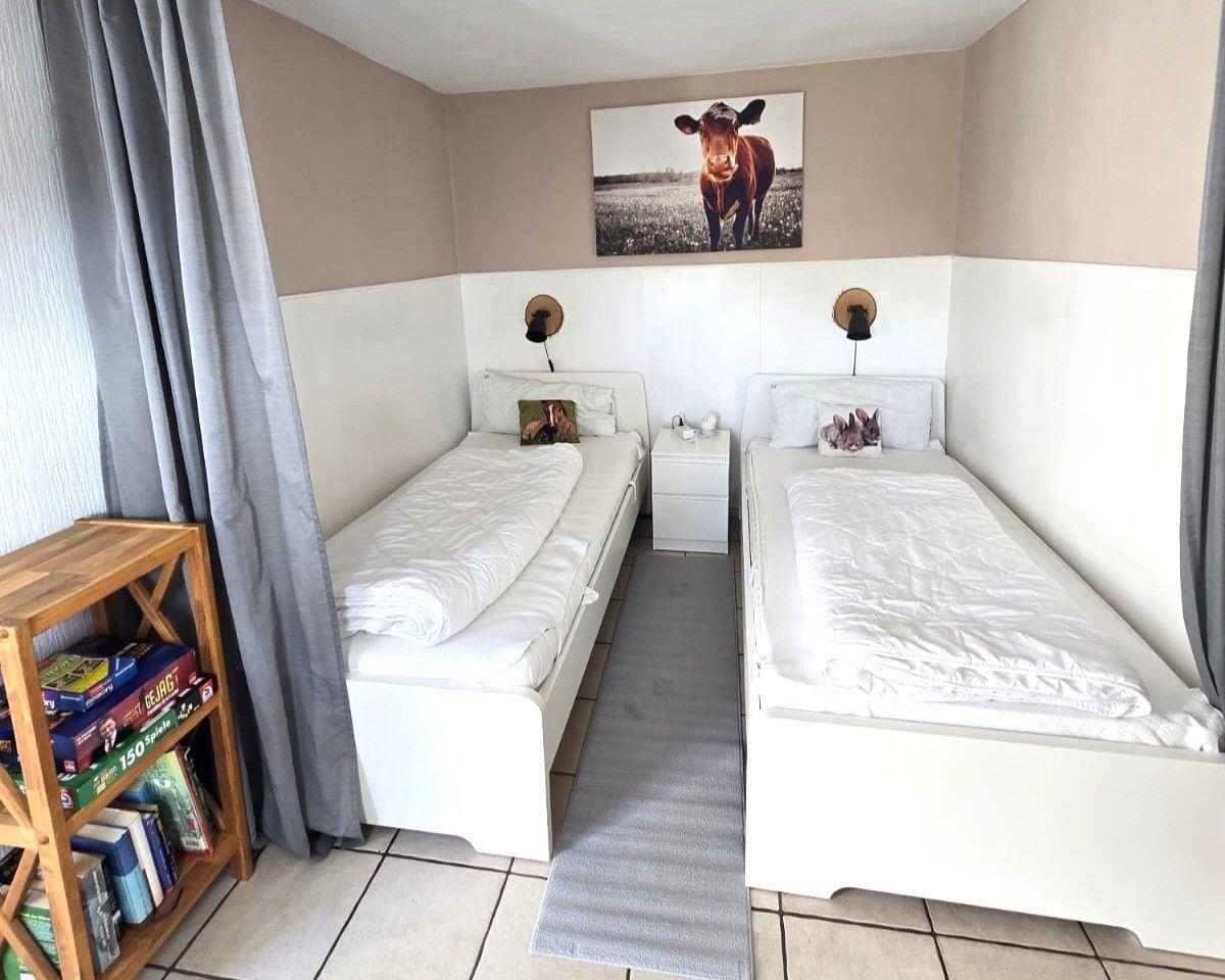 Two white single beds with white bedding are placed side by side.