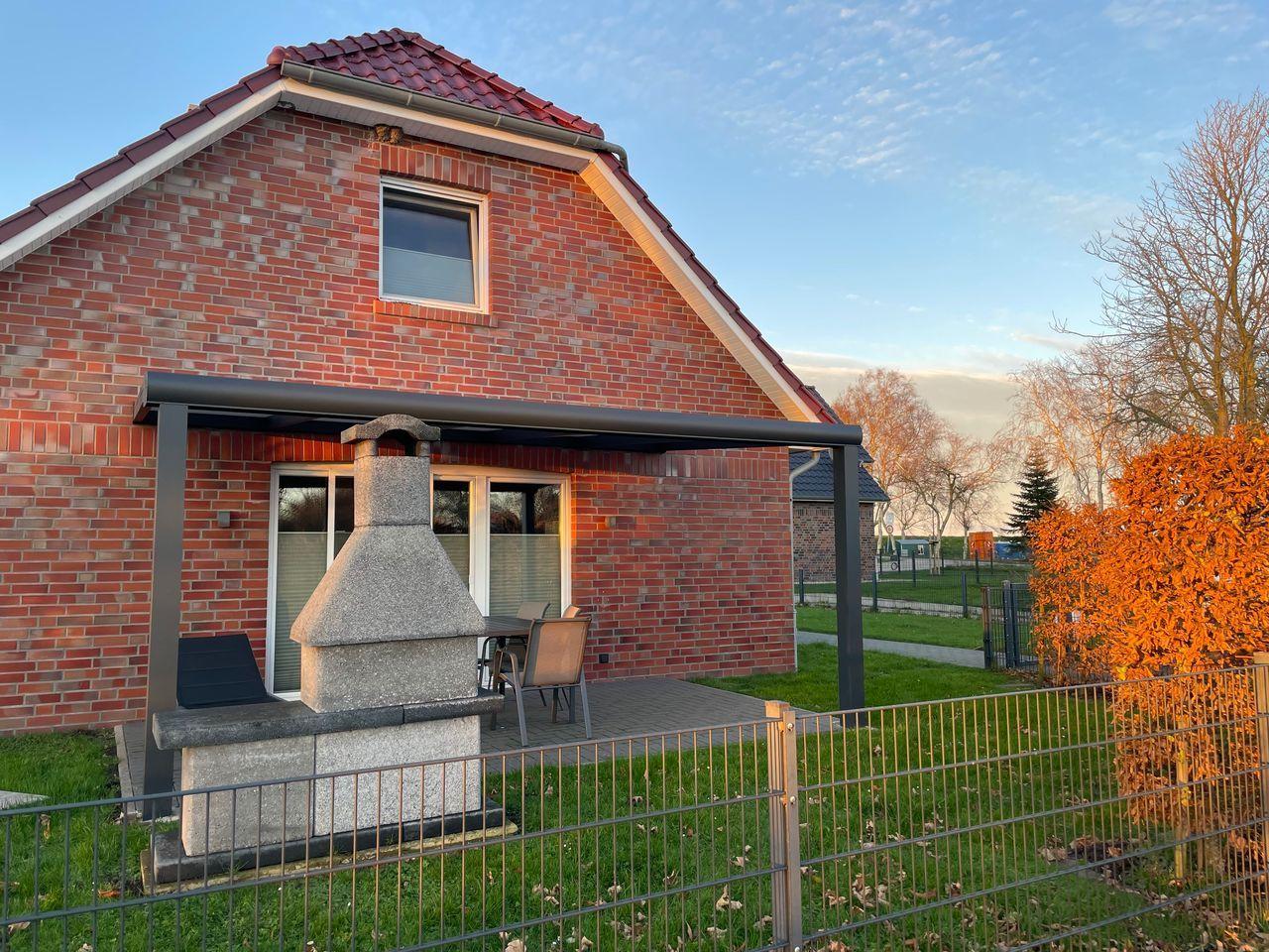 Rotes Backsteinhaus mit Terrasse und Grillplatz im Garten.