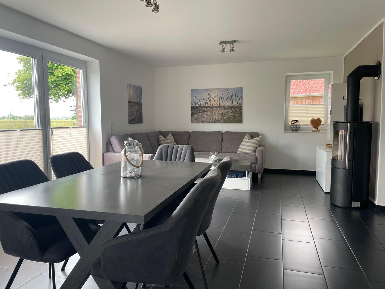 Essbereich mit Tisch und Stühlen, Wohnbereich mit Sofa und Kaminofen.