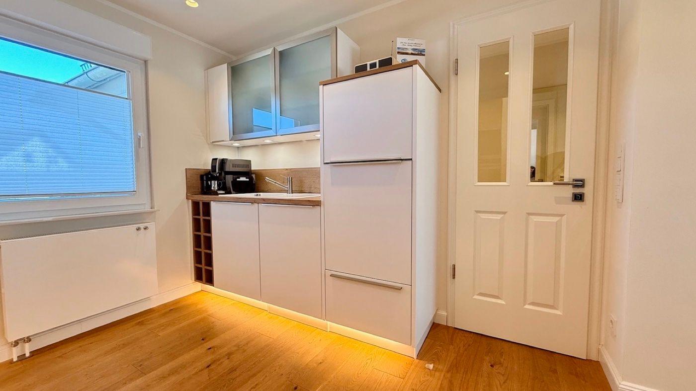 Küche mit Kühlschrank, Arbeitsfläche und Fenster