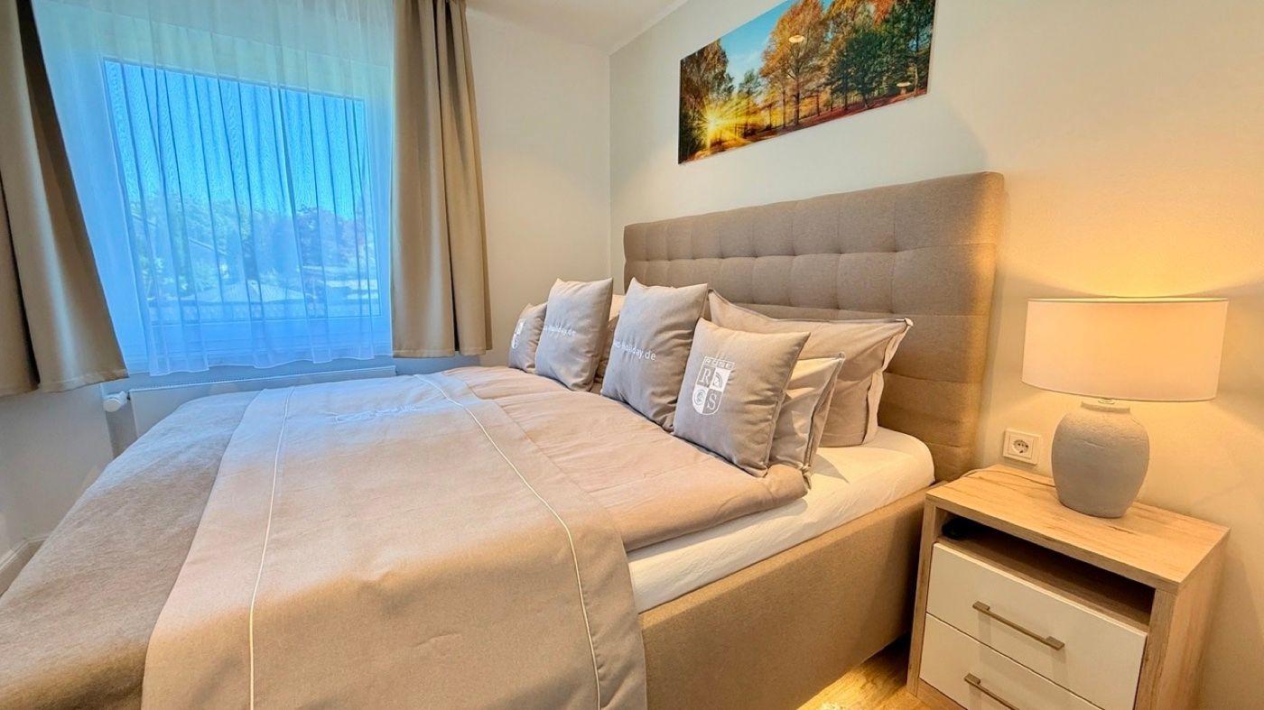 Schlafzimmer mit Bett, Nachttisch und Wandbild.